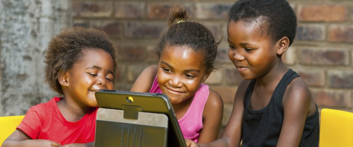 Portrait of three african girls playing leisure games on tablet.